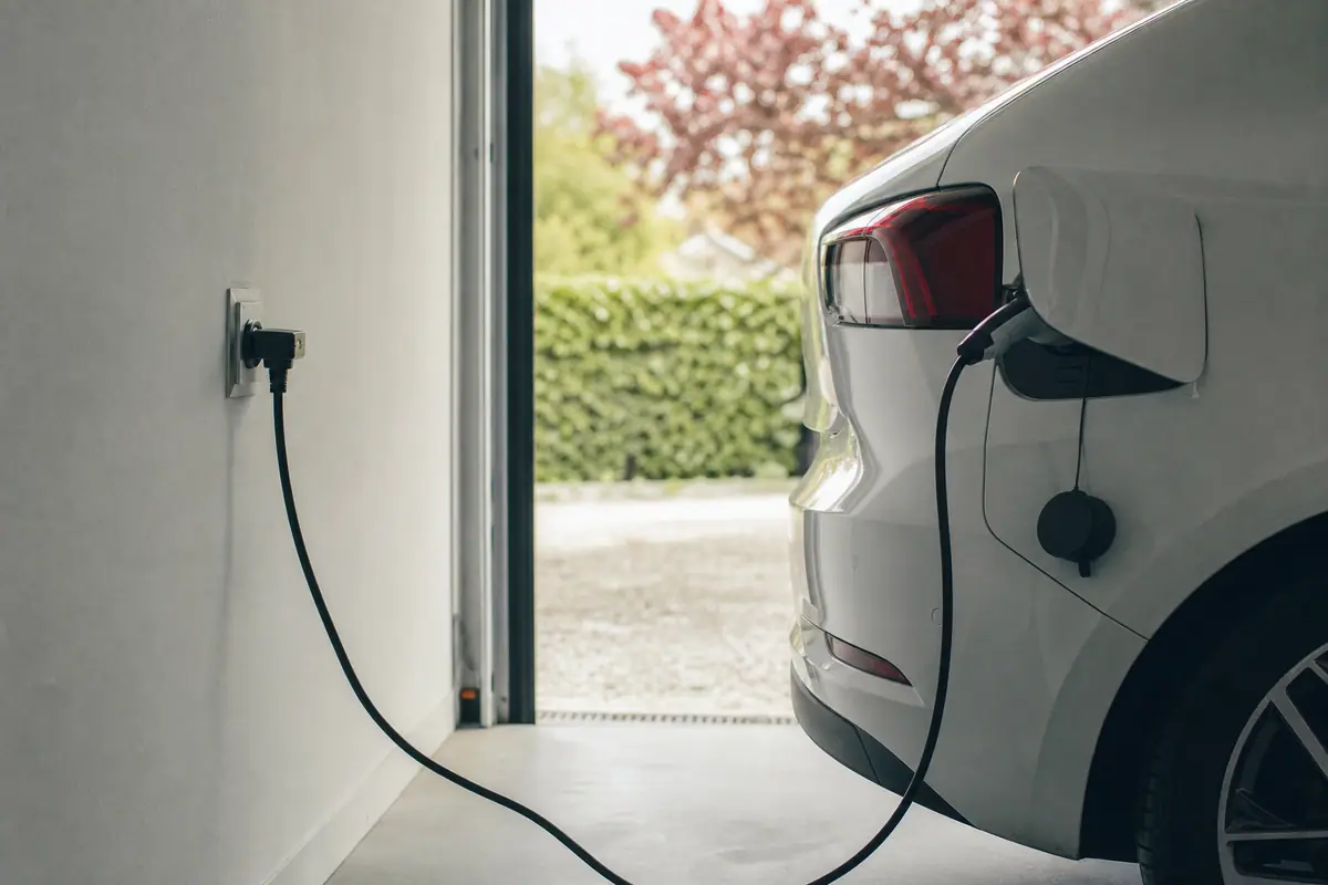 Voiture électrique branchée à une prise domestique dans un garage particulier