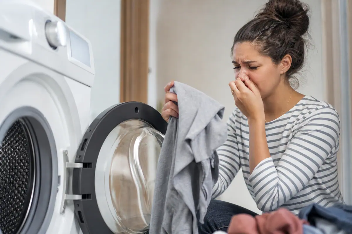 Linge propre plié à la sortie d'un lave-linge, porte du tambour ouverte au premier plan