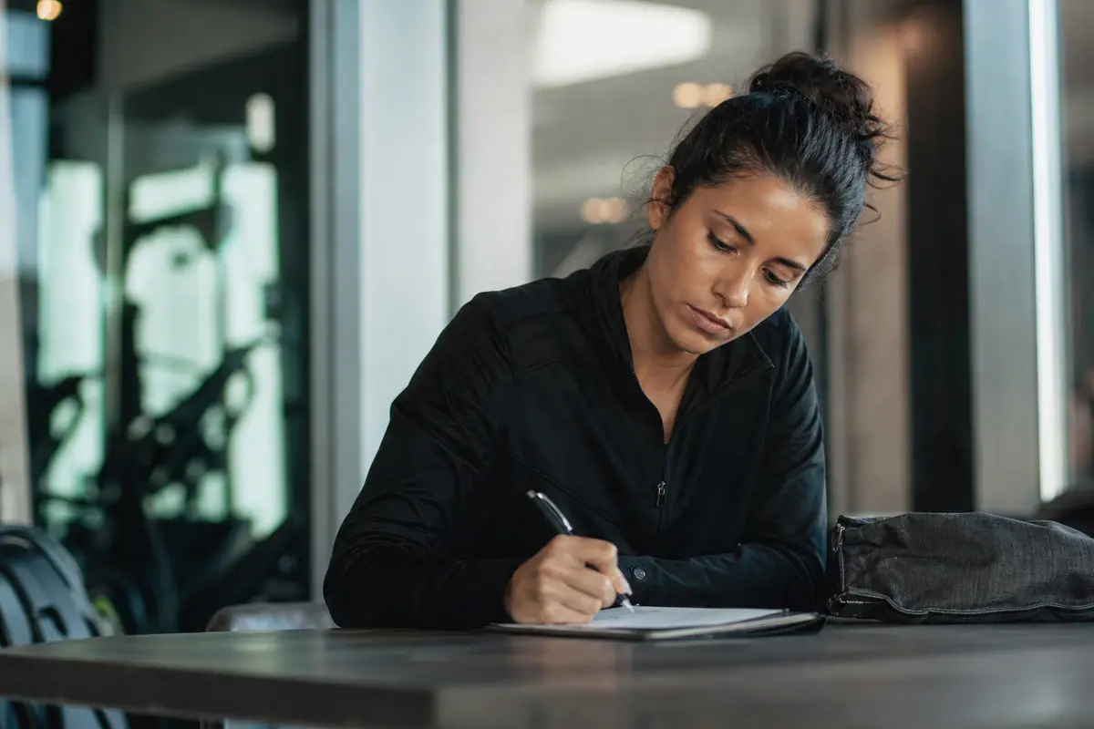 Personne remplissant un formulaire de résiliation à l'accueil d'une salle de sport