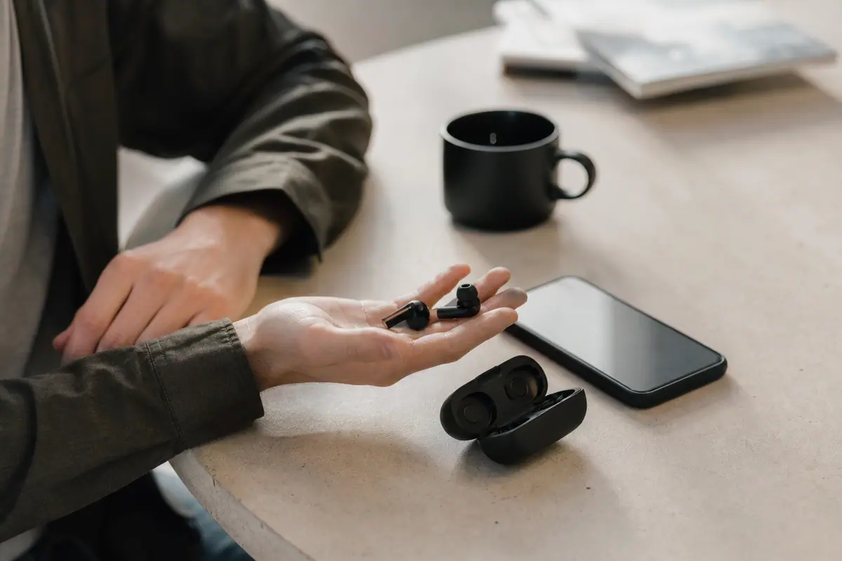 Personne ajustant des écouteurs sans fil dans la rue, smartphone à la main