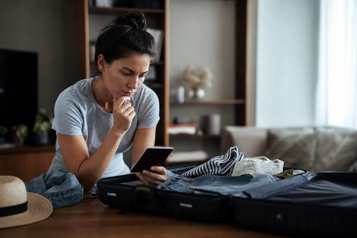 Passeport français posé sur une table à côté d'un billet d'avion et d'une valise