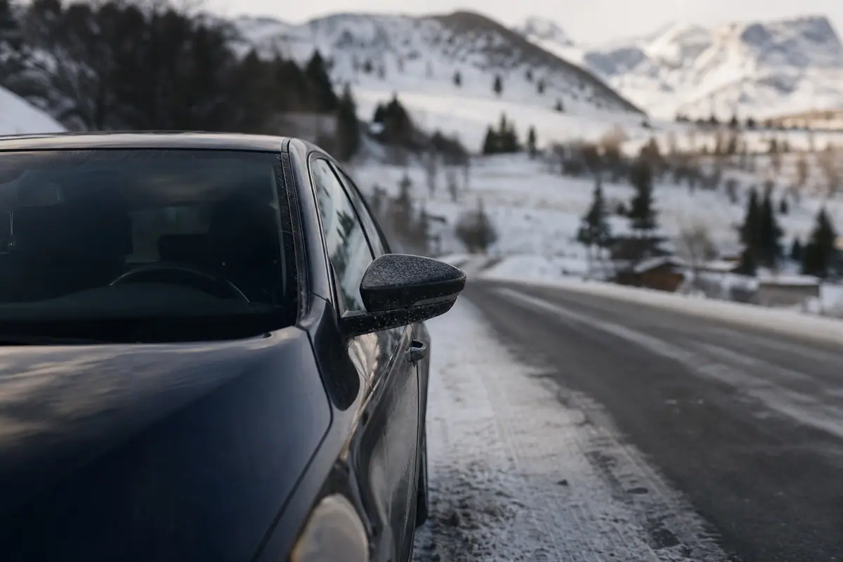 Voiture couverte de givre le matin sur un parking en hiver, jauge de carburant visible sur le tableau de bord