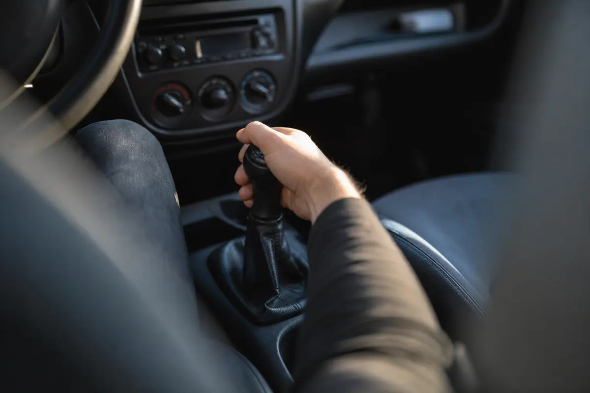 Main sur le levier de vitesses d'une voiture par un matin froid, pare-brise légèrement givré