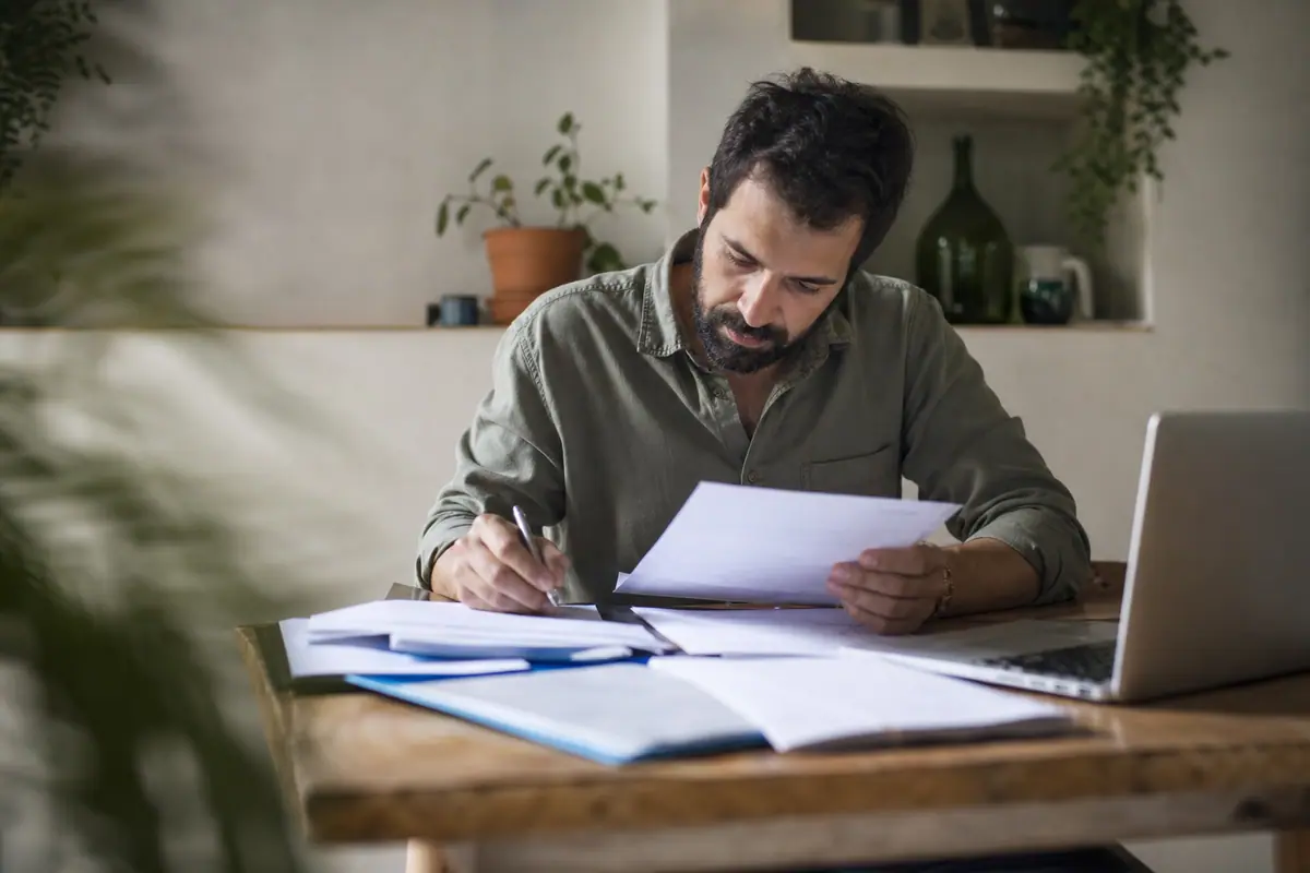 Personne consultant des documents comptables et fiscaux à une table, calculatrice à proximité