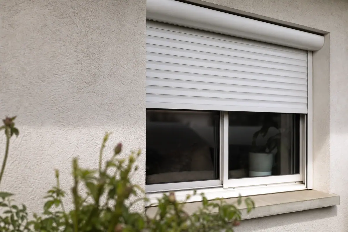 Volet roulant électrique à moitié fermé sur une fenêtre de maison