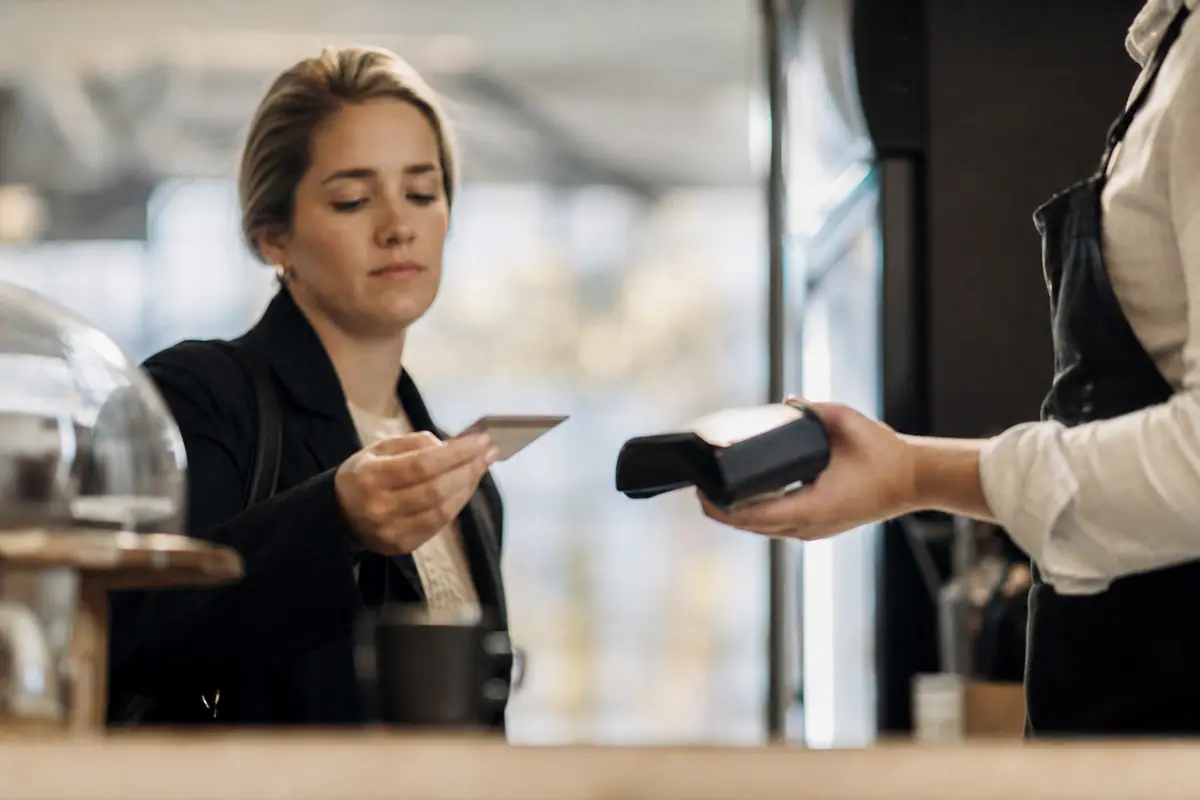 Carte bancaire présentée devant un terminal de paiement dans un magasin